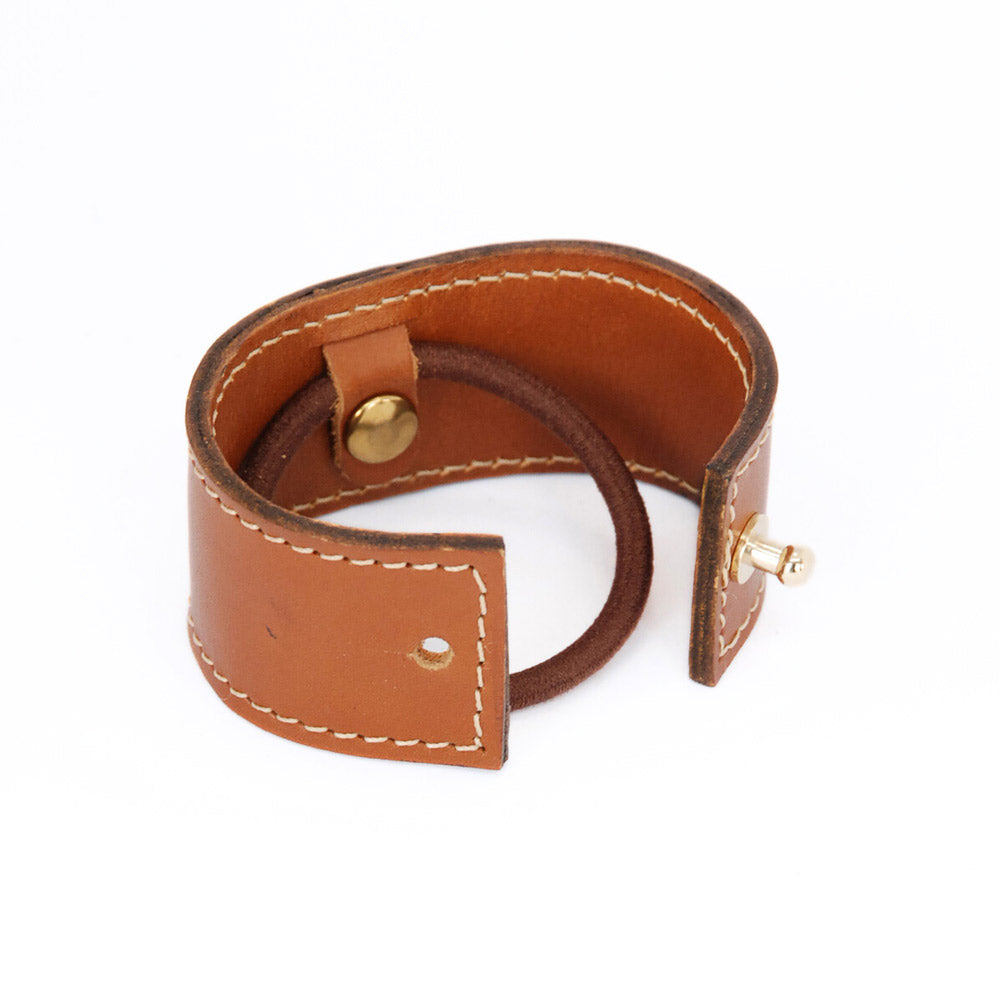 productshot tegen transparante achtergrond van leren short cover in cognac met witte stiksels. open, zo zie je het elastiek bevestigingssysteem en de sluitingsknopje.