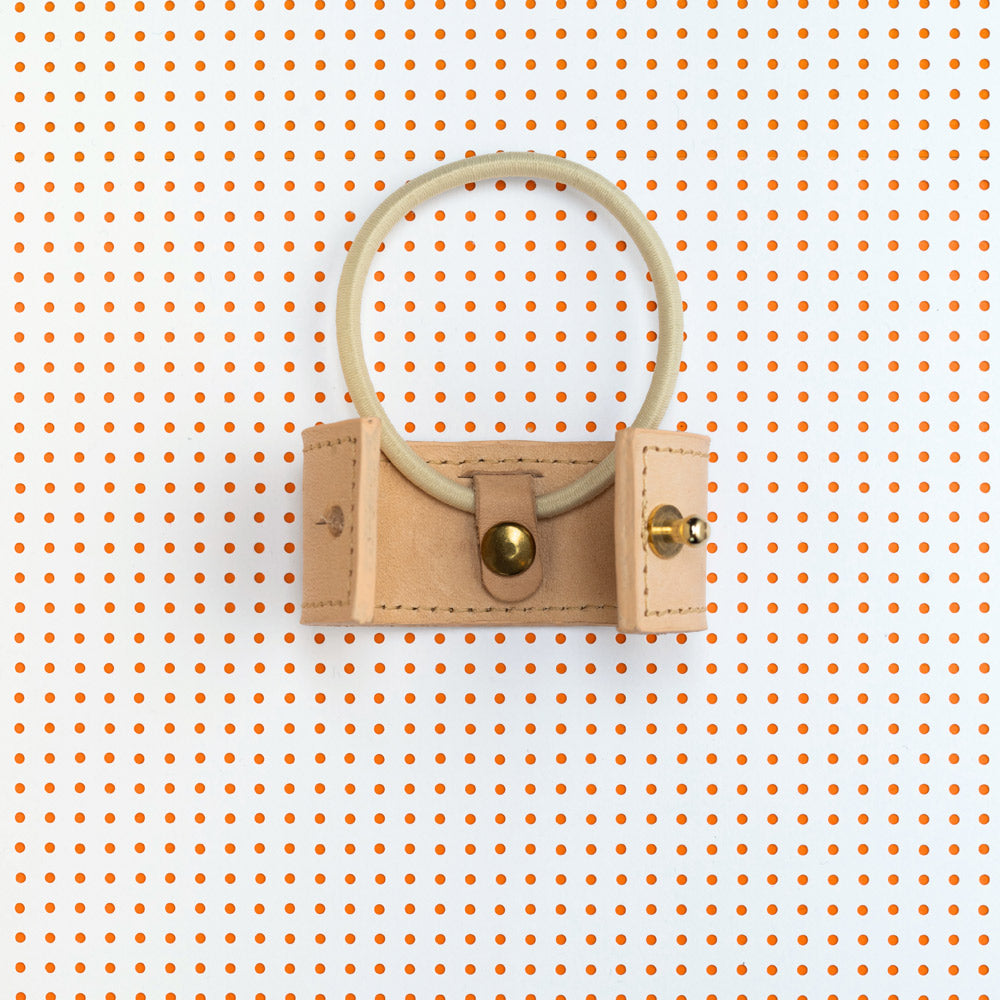 productfoto. Vooraanzicht leren short cover open met elastiek-vervangingssysteem zichtbaar, in kleur naturel. Achtergrond van het beeld is wit met organje stippen