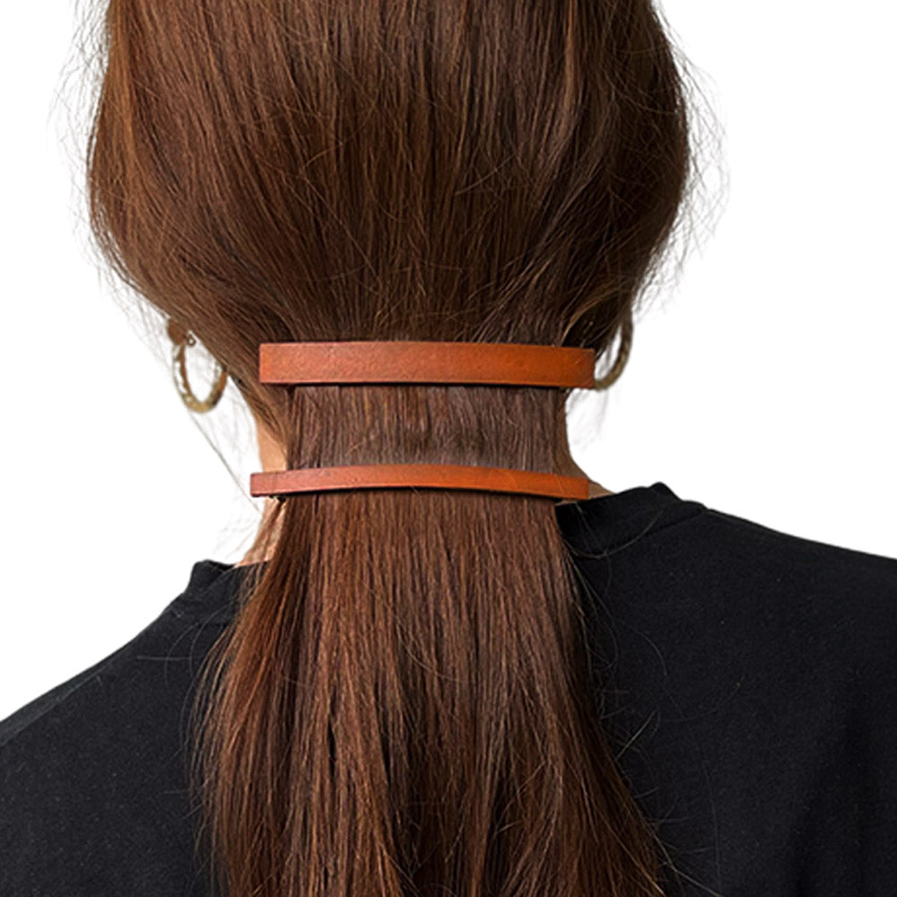 model met stijl lang bruin haar vastgezet in een lage staart met een dunne en een normale leren haarclip kleur cognac
