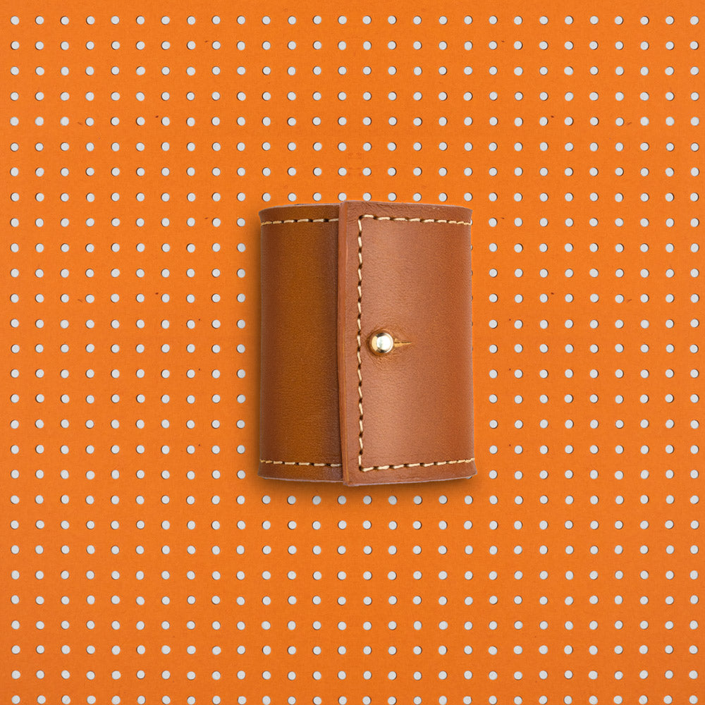 productfoto. Vooraanzicht leren long cover dicht, in kleur cognac. Achtergrond van het beeld is oranje met witte stippen