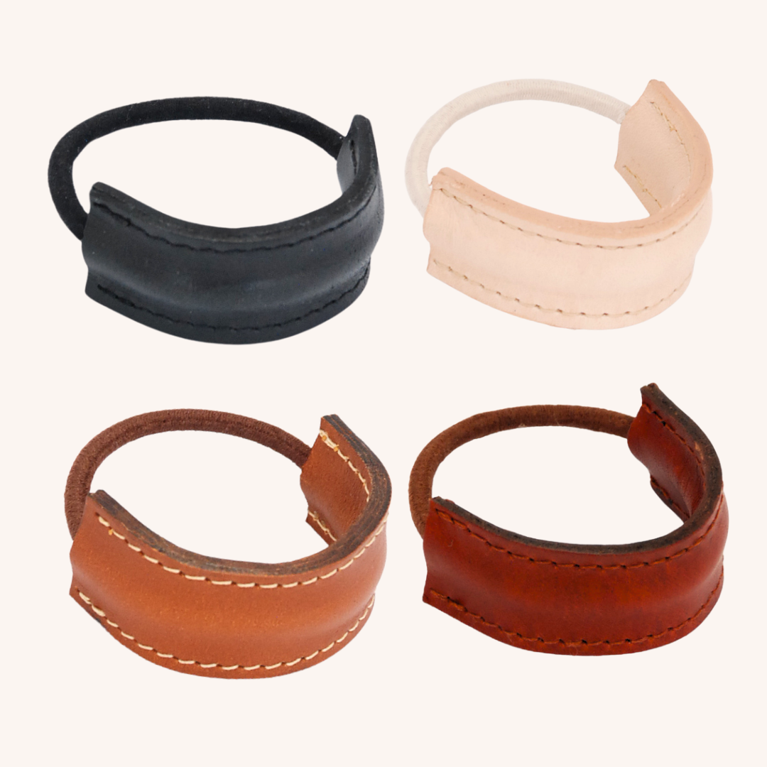 Beeld van 4 kleuren leren hair elastic covers uit de collectie tegen een licht gekleurde achtergrond. Van links naar rechts: naturel, zwart, cognac en sienna bruin