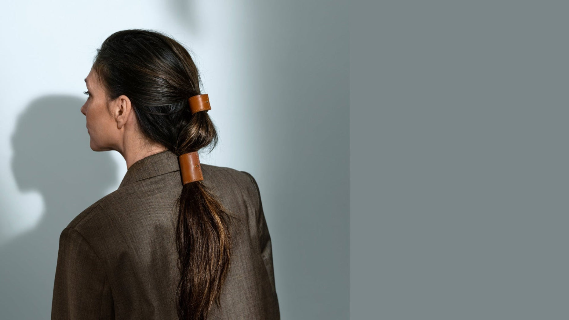 fashion model met lang donkerbruin haar, haarstyling is bovenkant haar en lage staart losjes vastgezet vastgezet met long cover en short cover in kleur cognac in maat L