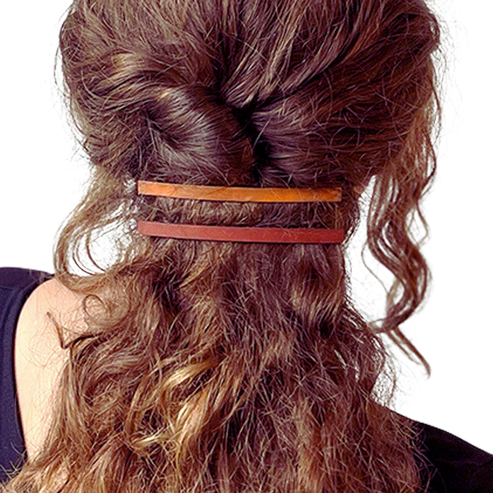 model met golvend lang bruin haar, vastgezet met twee dunne leren haarclips in kleuren Sienna bruin en cognac