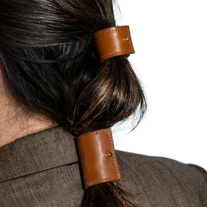 Close up kapsel van een model met dik bruin sluik haar. Haar is bovenop vastgezet met een korte cover kleur cognac en haar lage staart is vastgezet met een long cover in dezelde kleur. 